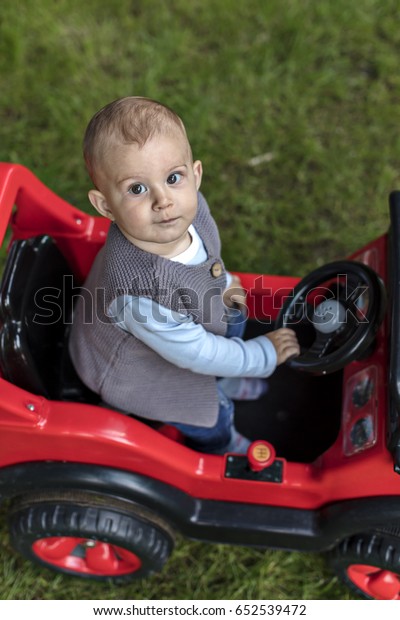 Little Boy on\
the Toy Electric Car in the\
Garden