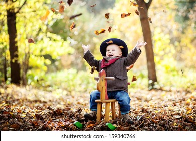 little boy on the wooden rocking horse in the autumn forest
