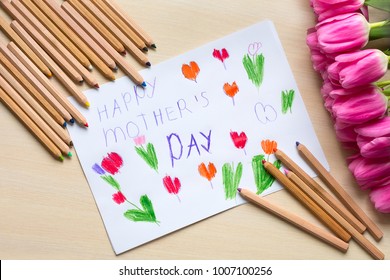 Little boy paints greeting card for Mom on Mother's Day with the inscription "Happy mother's day". Top view