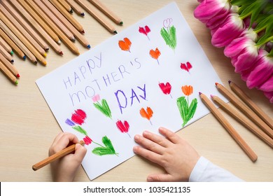 Little boy paints greeting card for Mom on Mother's Day with the inscription "Happy mother's day". Top view