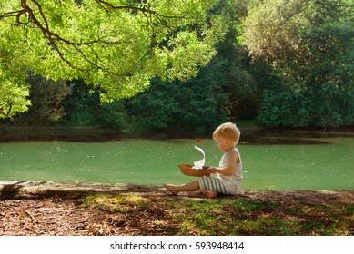 Little Boy With A Paper Boat In Summer Park Near Pond