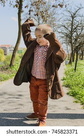 Little Boy In Park Wearing Oversized Clothes And Pretending To Be An Adult