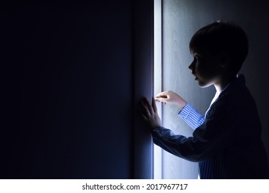 Little boy peeking through open door in darkness - Powered by Shutterstock