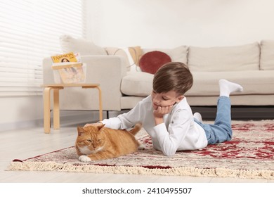 Little boy petting cute ginger cat on carpet at home - Powered by Shutterstock