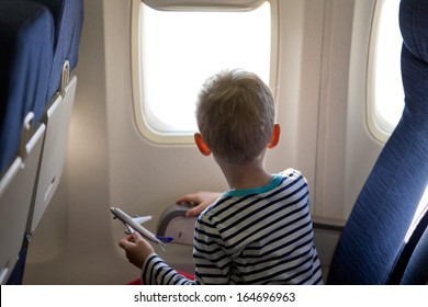 Little Boy In The Plane Looking Out The Window