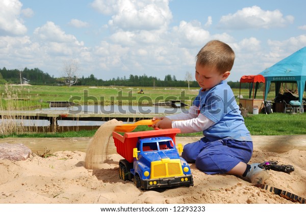 Little boy\
play in the sand box with color toy\
car