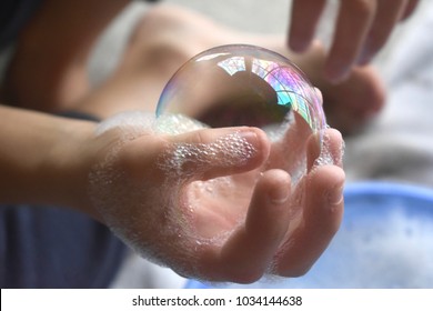 Little boy playing blowing and  making soap bubbles holding bubble in his hand