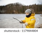 Little boy playing by Alpsee lake, located near Hohenschwangau and Neuschwanstein Castles. Bavaria, Germany. Child walk in windy and cold day