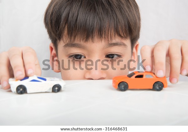 Little boy playing\
with car toy on  the\
table