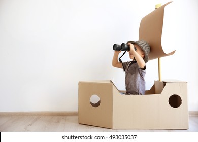 Little boy playing with cardboard ship on white wall background - Shutterstock ID 493035037