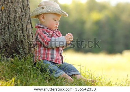 a little boy playing in a cowboy hat on nature