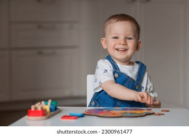 A little boy is playing educational logic games. Children's wooden toys. Sorter. Montessori for child development. - Powered by Shutterstock