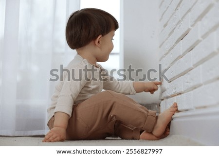 Little boy playing with electrical socket at home. Child in danger