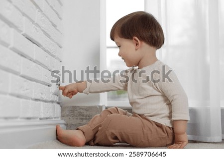 Little boy playing with electrical socket at home. Child in danger