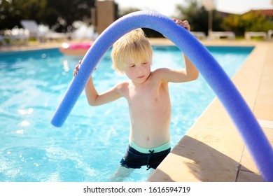 Little Boy Playing With Floating Noodle In Kids Pool During Holidays With Family In Greece. Lonely Child Is Bored. Upset Kid. Bad Mood.