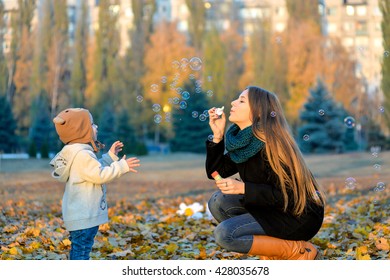 Little Boy Playing With His Sister In The Park In Autumn Girl Blowing Soap Bubbles Little Boy Playing With His Sister In The Park In Autumn Girl Blowing Soap Bubbles