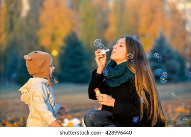 Little Boy Playing With His Sister In The Park In Autumn Girl Blowing Soap Bubbles Little Boy Playing With His Sister In The Park In Autumn Girl Blowing Soap Bubbles