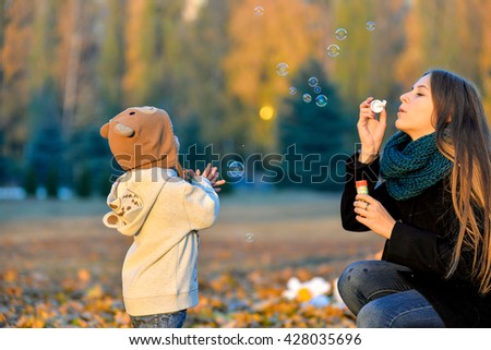 Little Boy Playing With His Sister In The Park In Autumn Girl Blowing Soap Bubbles Little Boy Playing With His Sister In The Park In Autumn Girl Blowing Soap Bubbles