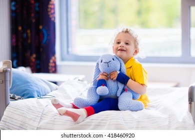 Little Boy Playing With His Toy In Bed In Hospital Room. Child With IV Tube And Pulse Oximeter In Modern Clinic. Kid Recovering From Sickness. Post Operative Care At Children Station. Kids Health Care