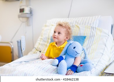 Little boy playing with his toy in bed in hospital room. Child with IV tube and pulse oximeter in modern clinic. Kid recovering from sickness. Post operative care at children station. Kids health care - Powered by Shutterstock