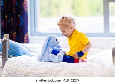 Little Boy Playing With His Toy In Bed In Hospital Room. Child With IV Tube And Pulse Oximeter In Modern Clinic. Kid Recovering From Sickness. Post Operative Care At Children Station. Kids Health Care