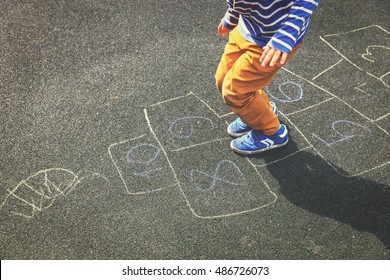 little boy playing hopscotch on playground