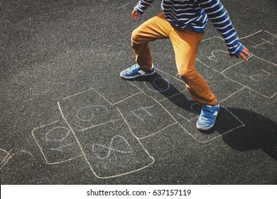 little boy playing hopscotch on playground