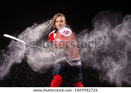 Little boy playing ice hockey at arena. A hockey player in uniform with equipment over a black background. The athlete, child, sport, action concept
