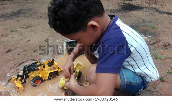 Little  boy\
playing in the mud with his mud\
vehicle