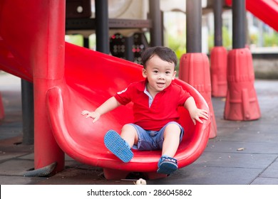 Little boy playing on children's slides. Outdoor portrait of a cute little asian boy at playground