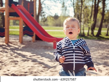 Little Boy Playing On Playground In The Spring. Crying Child Outdoors