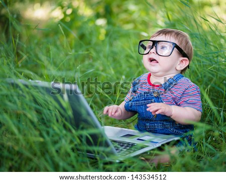 little boy playing outdoors with a laptop