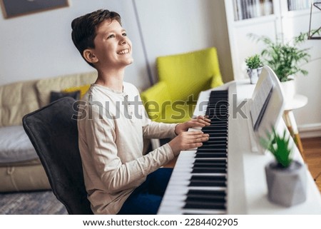 Little boy playing piano in living room. Child having fun with learning to play music instrument at home.