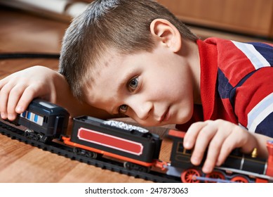 Little boy playing with railway lying on the floor
