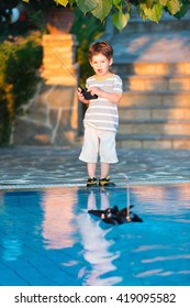 Little Boy Playing With Remote Control Boat By The Pool
