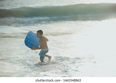 Little Boy Playing In The Sea On The Waters Edge While On Holiday In Australia.