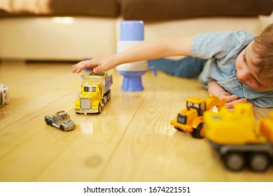 Little Boy Playing With Toy Car Truck On Wooden Floor. 