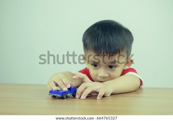 Little boy playing with toy car\
at home. Selective focus, Filtered image processed vintage\
effect.