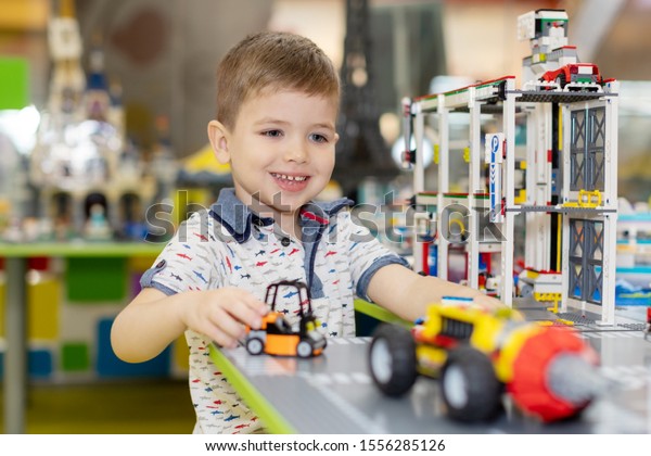 Little boy playing toy cars. Young kid with\
colorful educational vehicle and transport toys. Child driving car\
to rainbow parking garage. Kids at home or daycare. Kindergarten or\
preschool game.