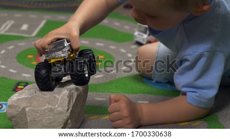 Little boy playing with toy truck car in his room alone. Child playing with toys (cars, trucks) indoor. Activities for kids at home