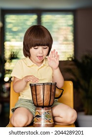 Little boy playing traditional african djembe drum at home. Child musical education and development