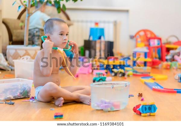 Little boy in the playroom\
with toys. room full of toys. Lots of toys, many cars piled on the\
floor