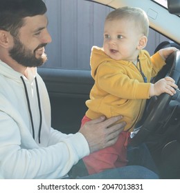 Little Boy Plays In The Car, Stands In Front Seat, Holding Wheel. Dad Supports Child. Father With Baby In The Car. Life Insurance Concept, Auto Insurance, Parenthood, Happy Family, Trip. Soft Focus.