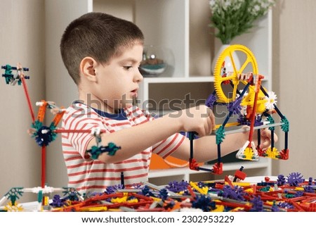 A little boy plays with a constructor, creating figures from gears and sticks. Development of logic and thinking in children