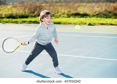 Little boy plays tennis outdoors.Copy space