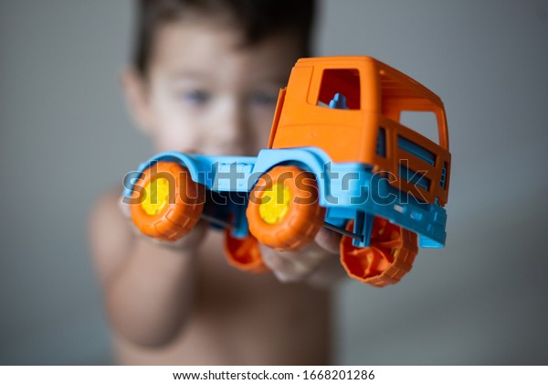 Little boy plays with toy car over grey
background isolated