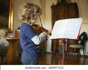 A little boy plays the violin at home. The child learns music. - Powered by Shutterstock