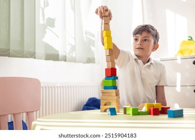 Little boy plays with wooden blocks at children's table in bright room. Focus on mental health and the role of speech therapy, psychological support and educational play. - Powered by Shutterstock