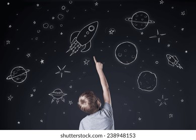 Little boy pointing at drawing sky at night