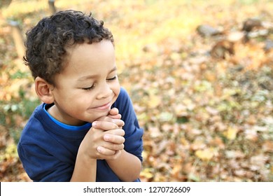little boy praying to God with hands together and a smile on his face with  head held high stock image stock photo photo